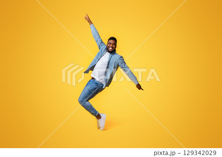 Cheerful Black Standing On Tiptoes, Fooling Over Yellow Background In Studio 129342029