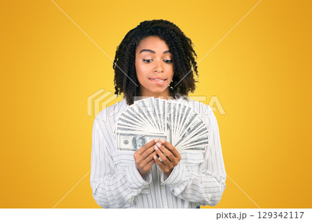 Rich Woman. Funny black girl holding money and biting lip over white background, free space 129342117