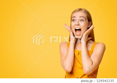 Crazy Sales. Emotional Young Woman Shouting At Copy Space With Excitement, Touching Her Face In Happy Shock, Yellow Background, Panorama Crazy Sales. Emotional Young Woman Shouting At Copy Space With Excitement, Touching Her Face In Happy Shock, Yellow Background, Panorama 129342135