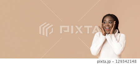 Cute Black Woman Laughing And Touching Her Cheeks On Yellow Background, looking at free space, panorama 129342148