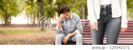 Breakup Concept. Unrecognizable Girlfriend Leaving Sad Boyfriend Sitting On Bench In Park Outside. Cropped, Selective Focus Breakup Concept. Unrecognizable Girlfriend Leaving Sad Boyfriend Sitting On Bench In Park Outside. Cropped, Selective Focus 129342171