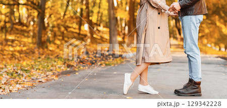 Cropped image of two lovers cuddling on golden forest path Cropped image of two lovers cuddling on golden forest path 129342228