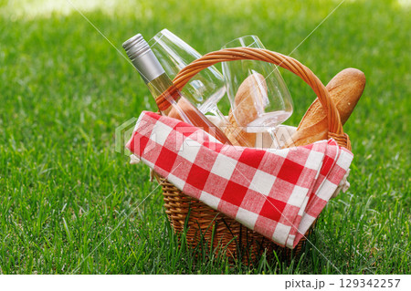Picnic basket with wine, grapes, and baguette 129342257