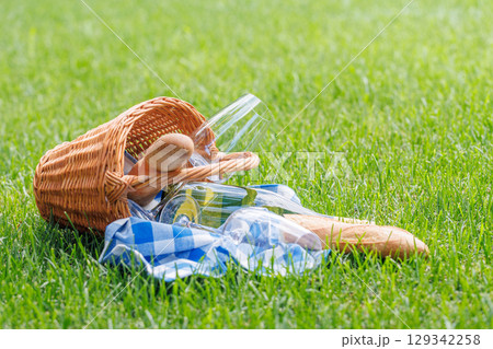 Picnic basket with wine, grapes, and baguette 129342258