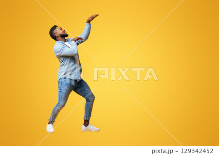 Funny african american man having fun and dancing in egypt style over yellow studio background, copy space Funny african american man having fun and dancing in egypt style over yellow studio background, copy space 129342452