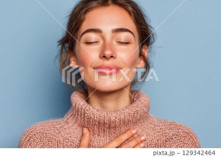 Young woman with closed eyes and hand on chest 129342464
