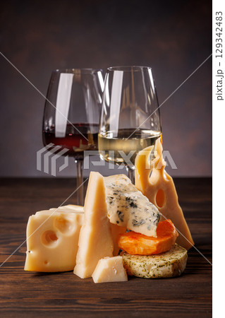 Assorted cheeses paired with glasses of wine on a rustic table Assorted cheeses paired with glasses of wine on a rustic table 129342483