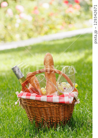 Picnic basket with wine, grapes, and baguette 129342671