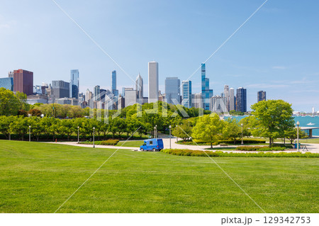 Sunny view of downtown Chicago with iconic skyscrapers rising above a lush green park meadow Sunny view of downtown Chicago with iconic skyscrapers rising above a lush green park meadow 129342753