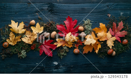 Vibrant red, orange, and yellow leaves are arranged with acorns and moss on a dark wooden background, showcasing the beauty of fall. Vibrant red, orange, and yellow leaves are arranged with acorns and moss on a dark wooden background, showcasing the beauty of fall. 129343178