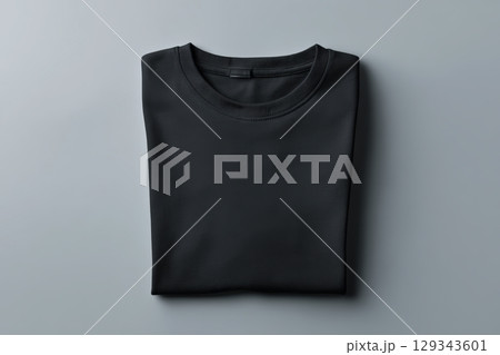 Folded black shirt displayed on a gray surface for minimalist aesthetic and styling inspiration Folded black shirt displayed on a gray surface for minimalist aesthetic and styling inspiration 129343601