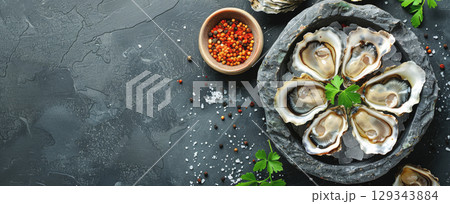Succulent oysters displayed on ice with various spices and fresh herbs, showcasing a gourmet seafood experience. 129343884