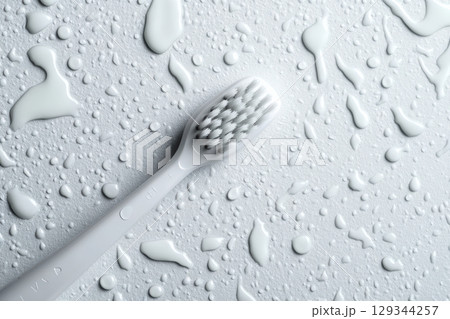 Close-up of a toothbrush and water droplets on a white surface after cleaning 129344257