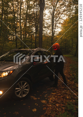 Autumn SUV with Driver with Pumpkin Head in Forest Autumn SUV with Driver with Pumpkin Head in Forest 129345210