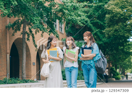 キャンパスで喋りながら歩く3人の大学生 キャンパスで喋りながら歩く3人の大学生 129347309