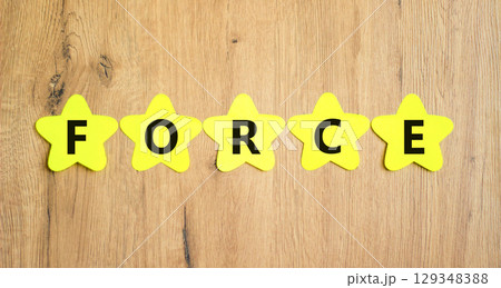 Force symbol. Concept word Force on beautiful yellow paper stars. Beautiful wooden table wooden background. Business lifestyle force concept. Copy space. Force symbol. Concept word Force on beautiful yellow paper stars. Beautiful wooden table wooden background. Business lifestyle force concept. Copy space. 129348388