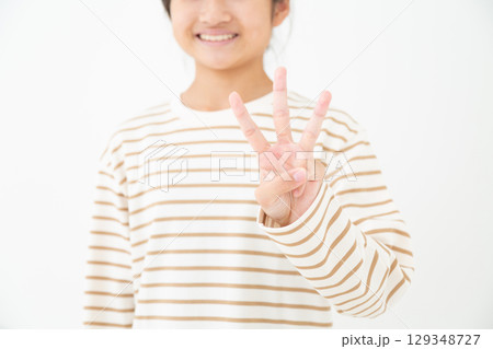 3本指を立てる中学生の女の子 129348727