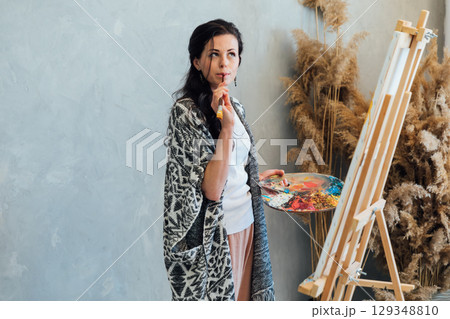 artist paints a picture on an easel with brushes and paints artist paints a picture on an easel with brushes and paints 129348810