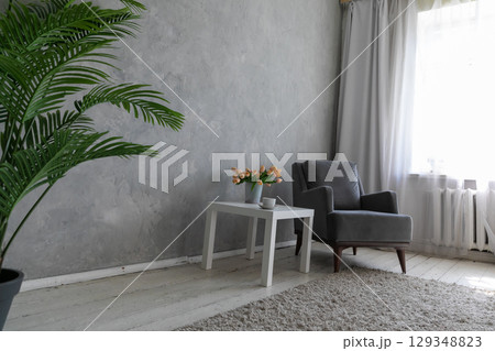 Armchair and table with a vase of flowers in the interior of a room Armchair and table with a vase of flowers in the interior of a room 129348823