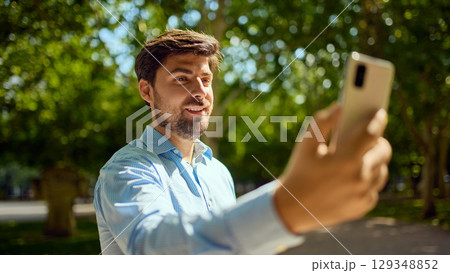 Smiling businessman making a video call outdoors on smartphone Smiling businessman making a video call outdoors on smartphone 129348852