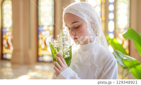 Catholic chrismation ceremony with teenager holding lilies of the valley flowers in church 129348921