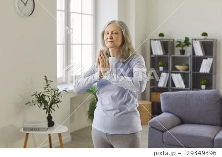 Yogi senior woman standing peacefully with hands in namaste pose, eyes closed, meditating Yogi senior woman standing peacefully with hands in namaste pose, eyes closed, meditating 129349396