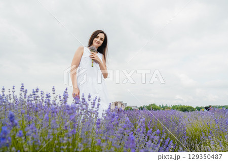 A young woman in a white dress stands in the lavender field A young woman in a white dress stands in the lavender field 129350487