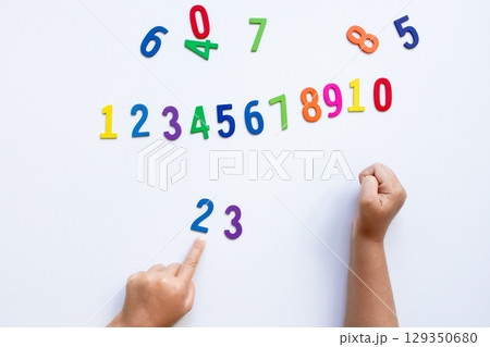 Child learning numbers with colorful wooden numerals on white background Child learning numbers with colorful wooden numerals on white background 129350680