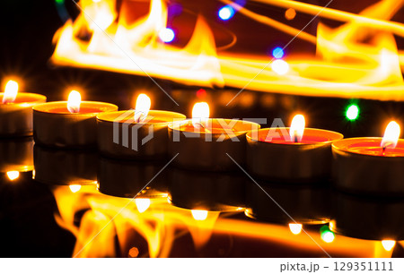 Countless small candles gently flicker in the deep darkness 129351111