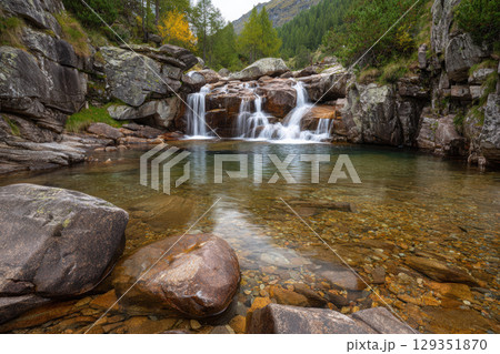 Mountain stream flows over smooth rocks in peaceful scene 129351870