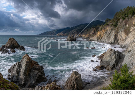Rugged cliffs and ocean waves under a moody sky 129352046