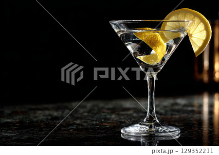 Elegant martini glass with lemon twist on glossy surface 129352211