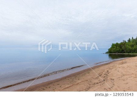 Serene Beachfront Overlooking Calm Waters Under a Cloudy Sky 129353543