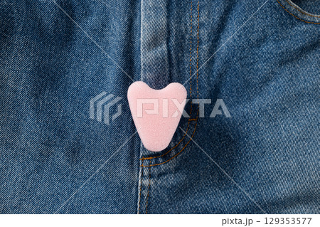 Female pink foam tampon stringless as heart on jeans. New generation. Hygiene accessories for women. View from above. 129353577