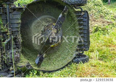 Close-up of lawnmower blade cutting fresh grass in garden setting 129353638
