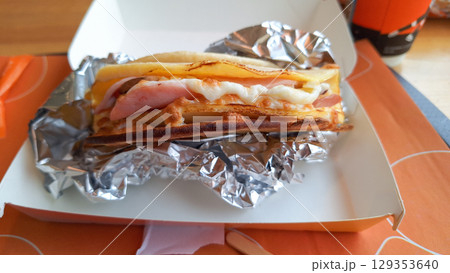 Delicious grilled ham and cheese sandwich in foil on orange table setting Delicious grilled ham and cheese sandwich in foil on orange table setting 129353640