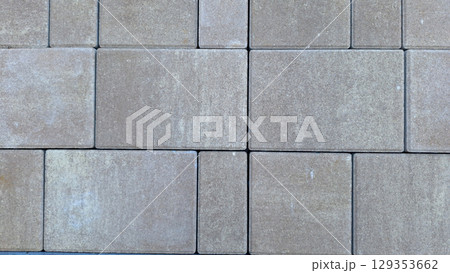 Uniform brown square concrete paver blocks arranged in seamless pattern 129353662