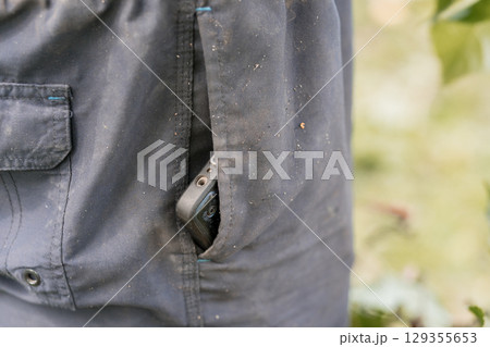 Rugged Outdoor Adventure: Gray Shorts Pocket Holds Smartphone, Close-Up, Forest Setting, Natural Light, Textured Fabric, Hiking and Technology Lifestyle. 129355653