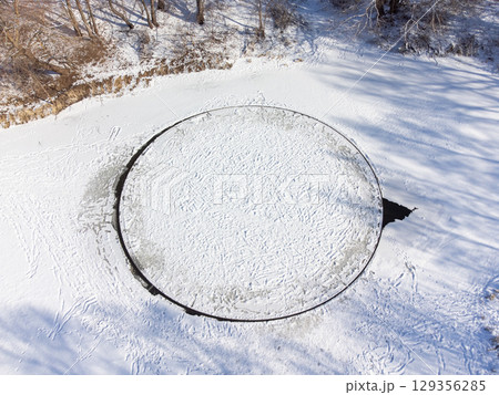 Aerial photo of spinning ice circle on river. Nature miracle on river in winter, perfect ice circle formed on water flow on small river 129356285