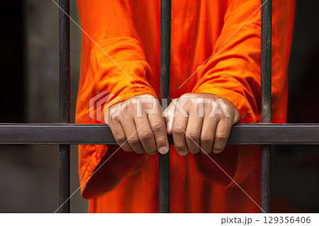 Prisoner behind bars. Male hands close-up. The grip on the bars symbolizes both strength and the yearning for liberation from captivity. 129356406