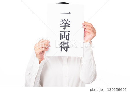 一挙両得と書かれた紙を両手で持つ白いシャツを着た人物 一挙両得と書かれた紙を両手で持つ白いシャツを着た人物 129356695