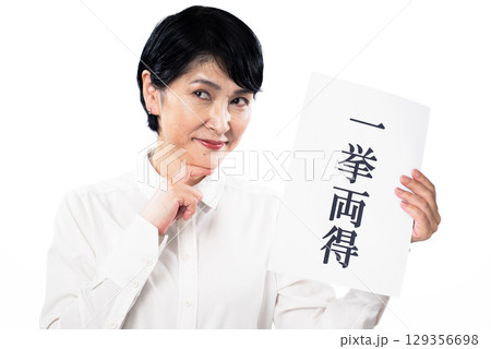 一挙両得と書かれた紙を持ちニヤリと笑う中年女性 129356698