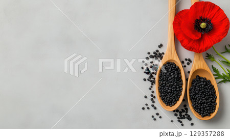 Wooden spoons with poppy seeds and red poppy flower on a grey background 129357288