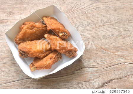 crispy fried salty chicken wing arranging in papay tray packaged on table 129357549