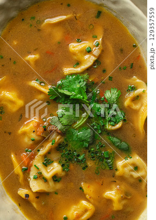 Bowl of soup with dumplings and fresh herbs 129357559
