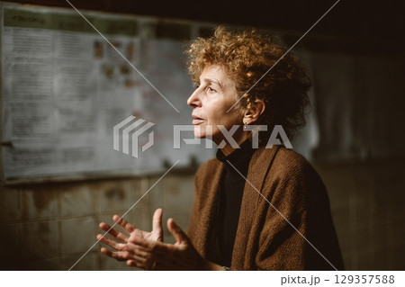 Mid-aged woman with natural curls speaking to a small group in a community center, generated AI Mid-aged woman with natural curls speaking to a small group in a community center, generated AI 129357588