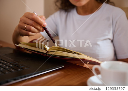 Woman Writing Notes in a Journal While Working at Home Woman Writing Notes in a Journal While Working at Home 129358797