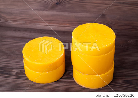 Yellow discs of beeswax on wooden background. Used natural bright yellow beeswax in disks Yellow discs of beeswax on wooden background. Used natural bright yellow beeswax in disks 129359220