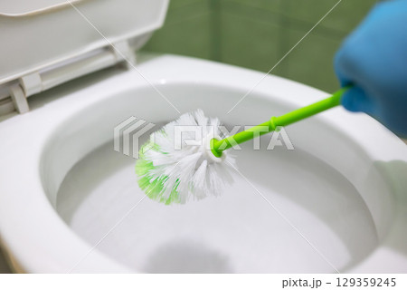 Housekeeper cleaning toilet with a brush. Keeping toilet clean and sanitized, regular cleaning of toilet Housekeeper cleaning toilet with a brush. Keeping toilet clean and sanitized, regular cleaning of toilet 129359245