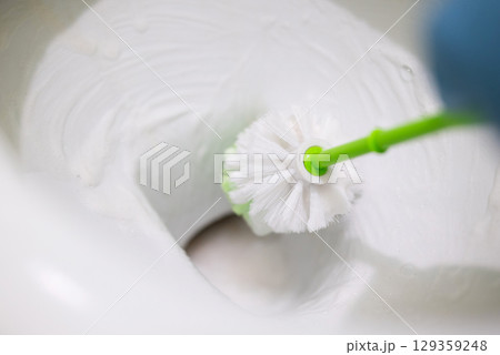 Close up of cleaning toilet with brush and foam. Sanitizing toilet, man cleaning water lime from lavatory pan 129359248
